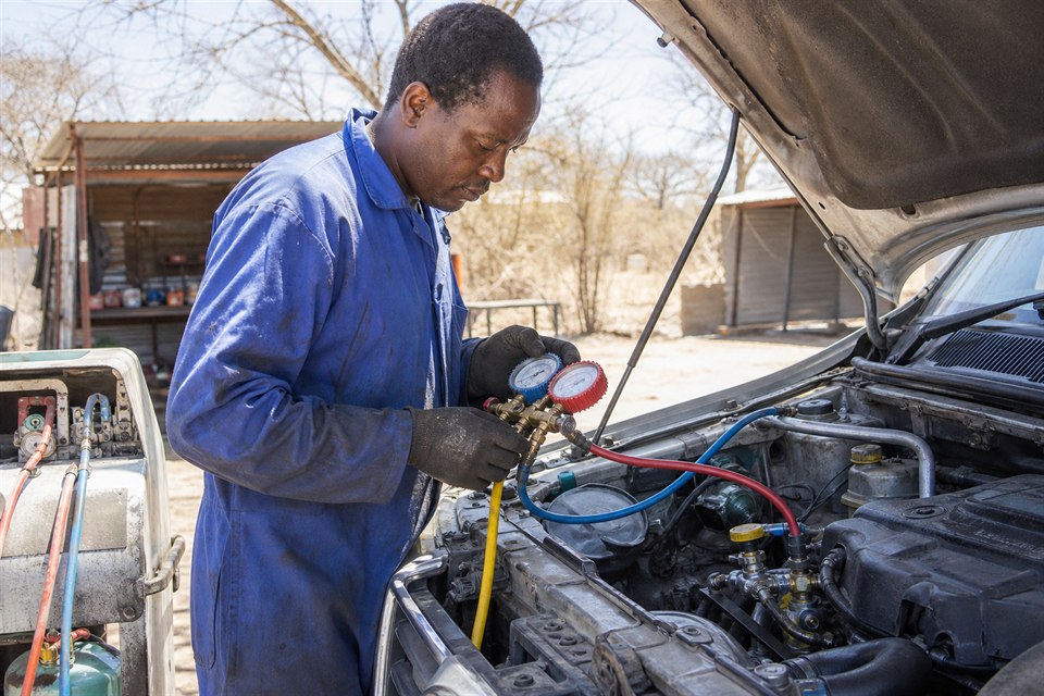 Technician servicing a vehicle air-conditioning system outdoors